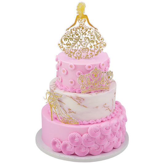 Tiered pink and white cake decorated with gold Quinceañera toppers: girl, crown, and high heel.