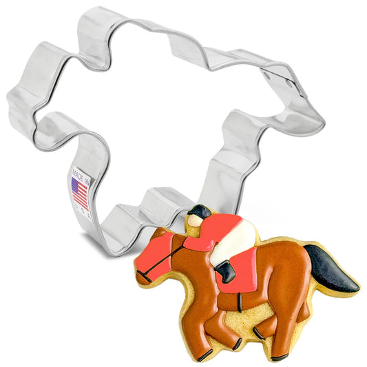 Silver racehorse-shaped cookie cutter shown beside a decorated horse cookie with brown icing, red saddle blanket, black mane and tail, and a small rider detail on a white background.
