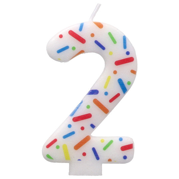Candle shaped like the number 2 with colorful sprinkles on a white background