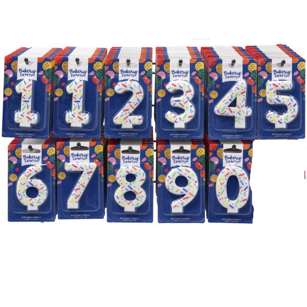 Counter display rack holding assorted Bakery Crafts rainbow sprinkle number candles in individual blue packages, showing digits 0 through 9 across two rows.