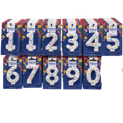 Counter display rack holding assorted Bakery Crafts rainbow sprinkle number candles in individual blue packages, showing digits 0 through 9 across two rows.