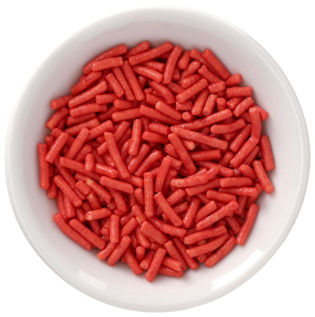 White bowl filled with soft red Natural Dyed Made Simply™ rod-shaped sprinkles, shown in a close-up overhead view on a white background.