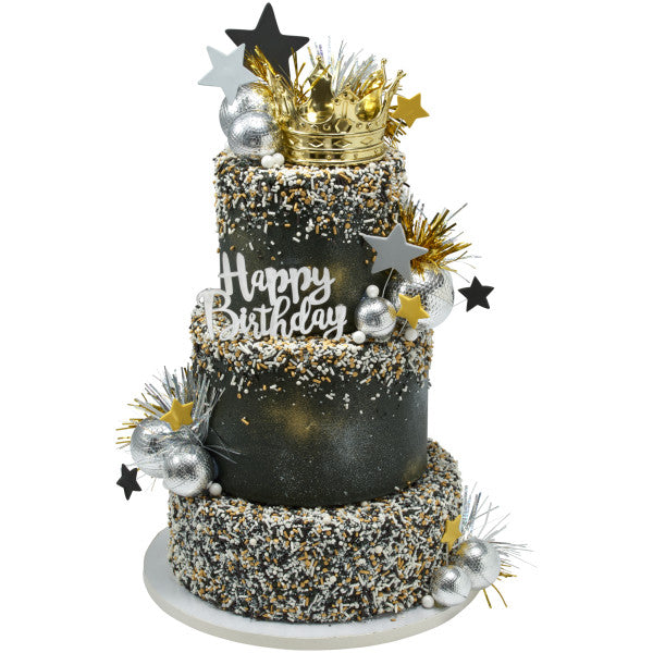 A glamorous black and gold cake adorned with stars, sprinkles, and a crown on top.