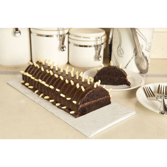 Chocolate Rehrücken cake topped with slivered almonds and sliced to show interior texture, displayed on a white board in a kitchen setting.