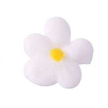 Close-up of a delicate royal icing flower in white with a yellow center.