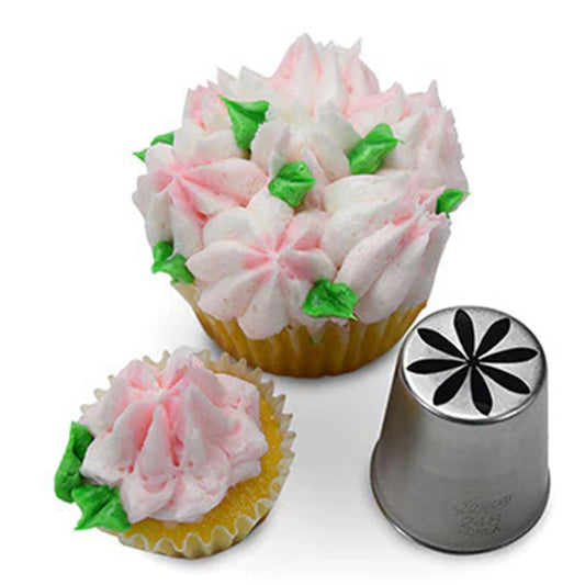 Metal Russian piping tip with an eight-petal flower cutout shown beside cupcakes topped with pale pink buttercream flowers and small green leaves on a white background.