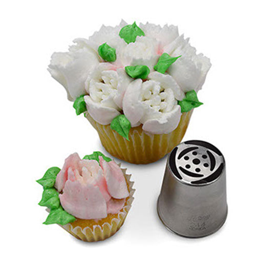 A Russian piping tip next to two cupcakes decorated with tulip-shaped buttercream flowers in white and pink, showcasing the delicate floral design created by the tip.