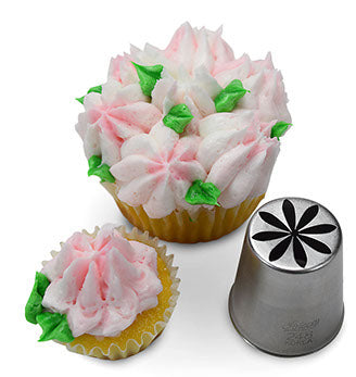 Cupcake with pink and white multi-petal flower decoration made with Russian piping tip #248, placed next to the piping tip showcasing its starburst floral design cut-out.