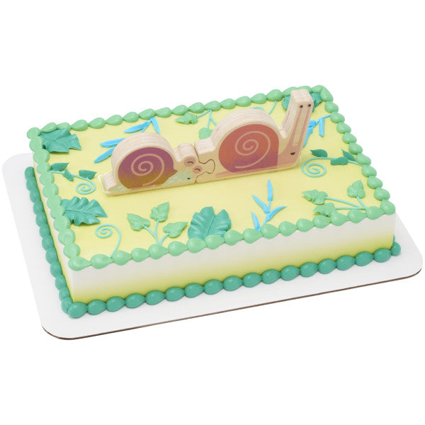 A nature-inspired cake with green foliage decorations and the wooden snail puzzle topper.