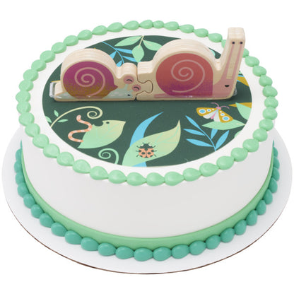 A garden-themed cake featuring a dark green background with leaves, insects, and the wooden snail topper.