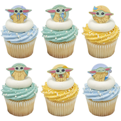 Six cupcakes with blue, mint, and yellow buttercream swirls topped with white pearl sprinkles and Grogu cupcake rings from The Mandalorian.