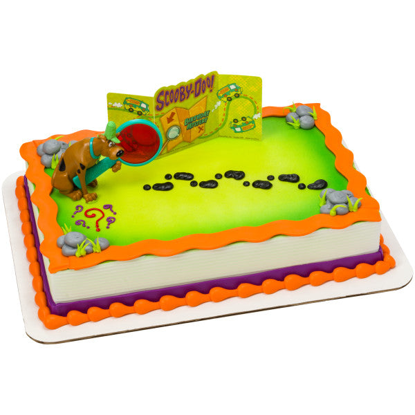 Scooby-Doo-themed birthday cake featuring Scooby figurine, detective glass, and a mystery map with footprints and colorful borders.