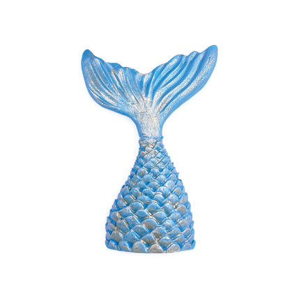 Blue mermaid tail decoration with textured scales and fin details highlighted with shimmering silver edible luster dust on a white background.