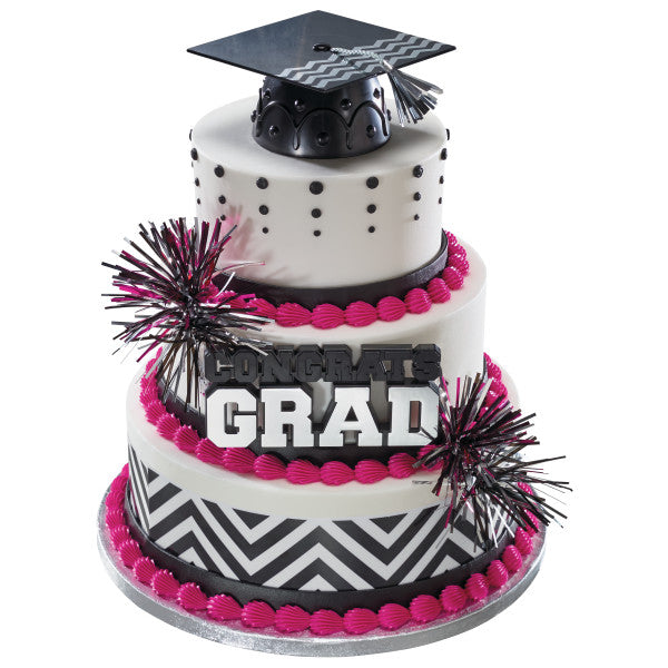 Tiered graduation cake decorated with silver and black elements, topped with mylar spray picks