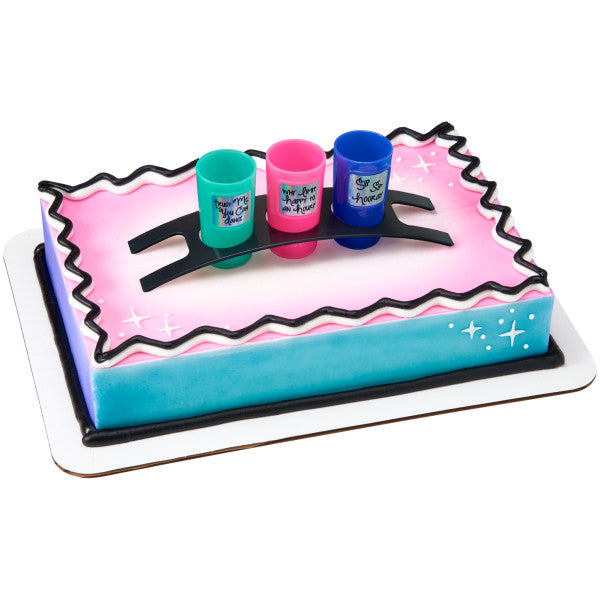 A gradient pink and blue cake with the shot glass set placed on top.