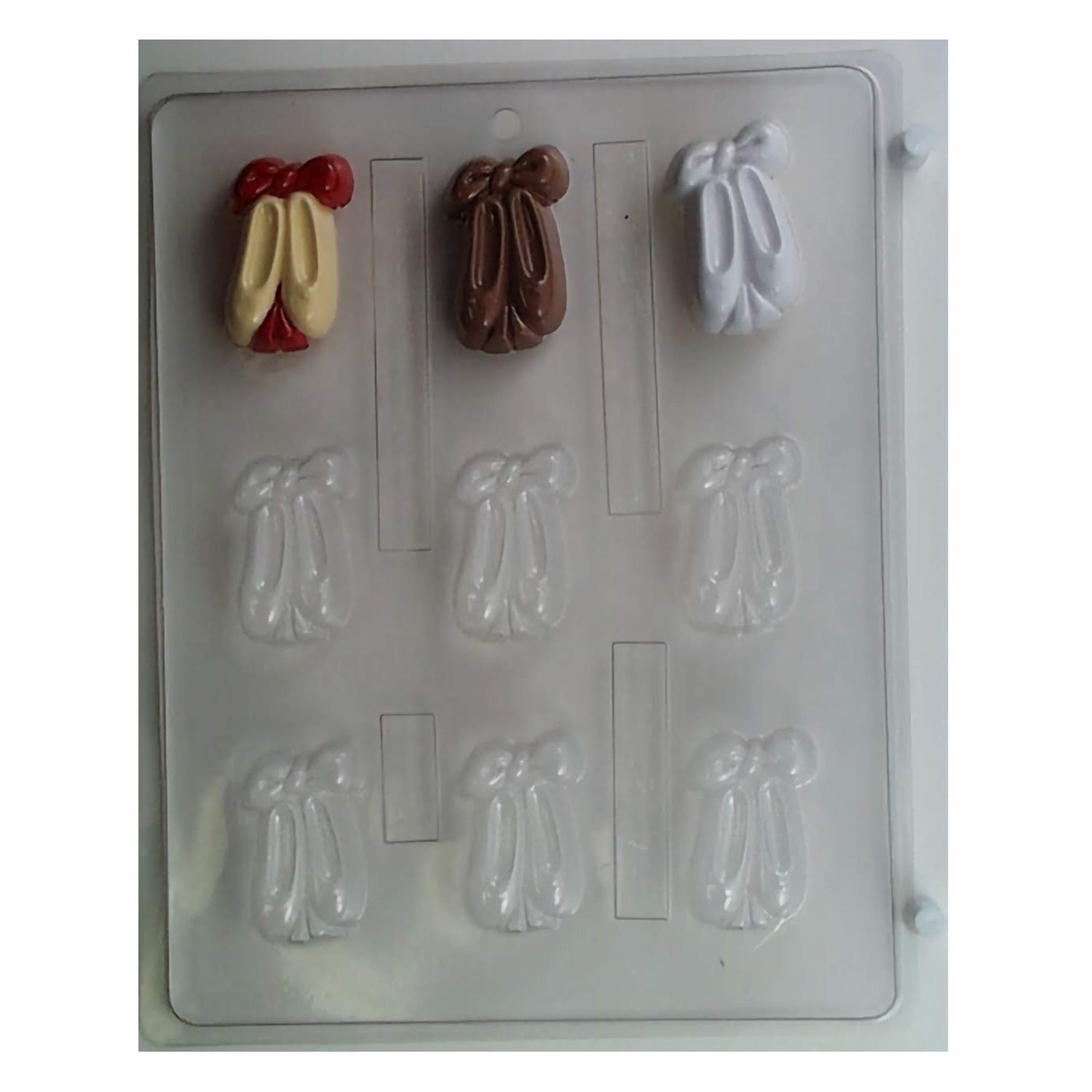 A delicate chocolate mold featuring several cavities in the shape of ballet slippers with bows. The mold captures the graceful curves and details of ballet footwear.