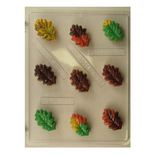 Chocolate mold sheet for creating small oak leaf-shaped confections, with multiple cavities displaying intricately detailed veins of the leaves. The mold includes finished examples in autumnal colors such as yellow, green, red, and brown, emphasizing the seasonal theme of the mold suitable for fall festivities and decorations.