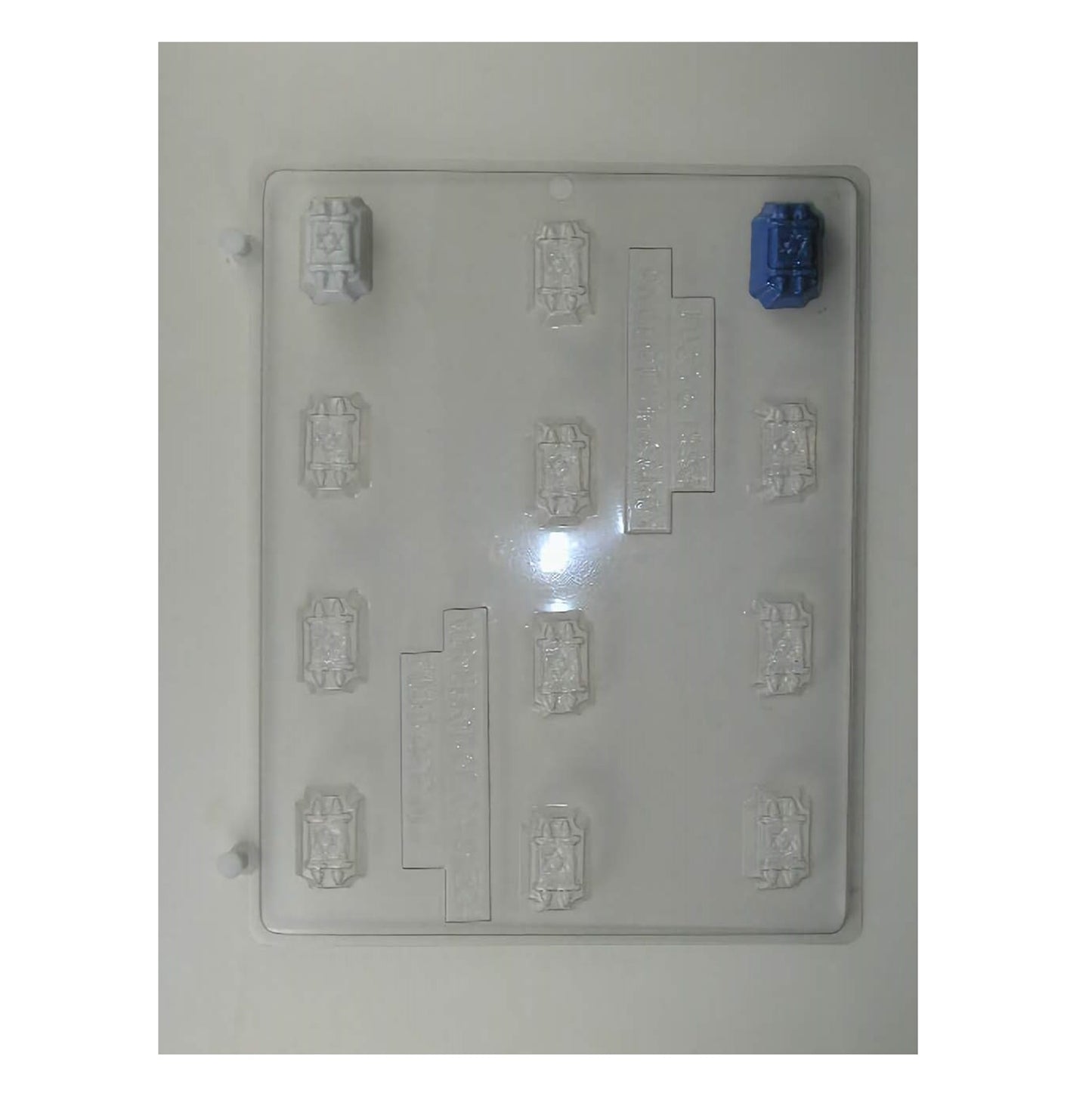 A clear plastic mold for crafting small chocolate scrolls resembling the Torah, complete with etched details representing the text and handles, fitting for religious celebrations, Bar or Bat Mitzvahs