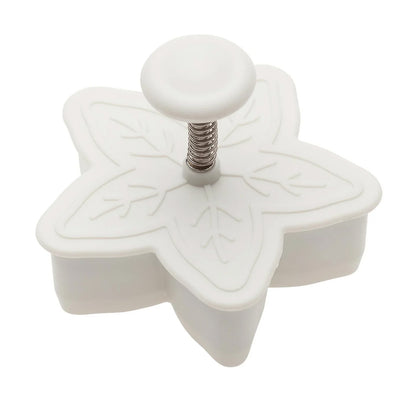 White 2-inch snowflake plunger cutter with a round button and visible spring mechanism on top, shown on a white background.