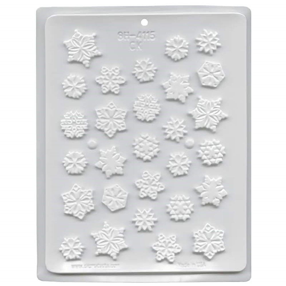 A white hard candy mold with cavities shaped like snowflakes. The snowflakes are in a variety of shapes and sizes. 