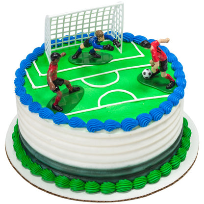 Round soccer-themed cake with white icing, green and blue trim, and three soccer player toppers on a field design.