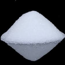 Pile of white sodium citrate powder on a black background, used as a food additive for gummies, candy, and pH control in culinary applications.
