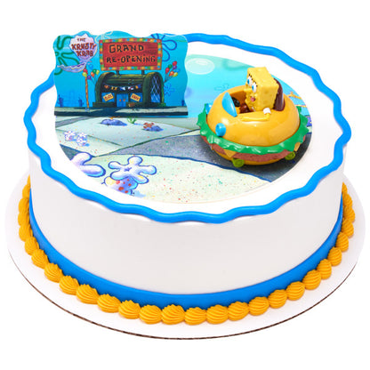 Round cake featuring the SpongeBob SquarePants™ cake topper set, a blue wave border, and a Krusty Krab edible image design.