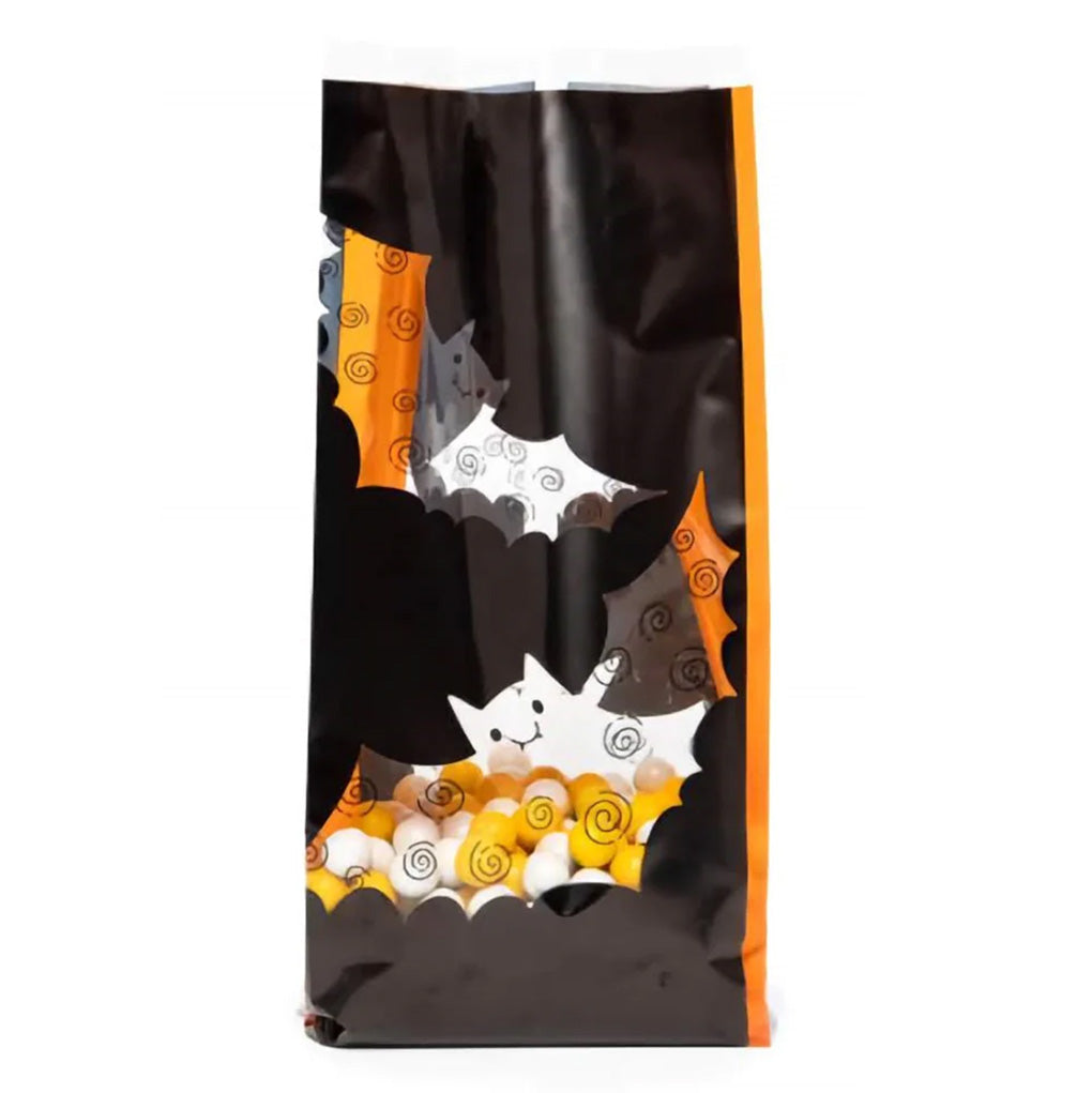 Large clear cello treat bag with black and orange Halloween bat cutout-style graphics, filled with candy corn and round white candies, standing upright on a white background.