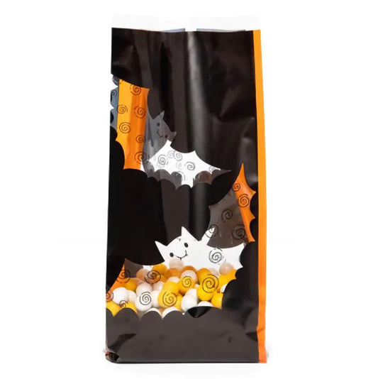 Large clear cello treat bag with black and orange Halloween bat cutout-style graphics, filled with candy corn and round white candies, standing upright on a white background.