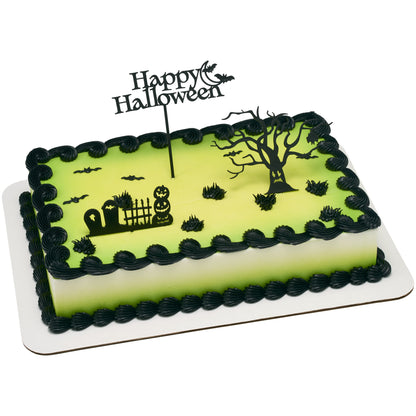 Rectangular green and black Halloween sheet cake decorated with a haunted tree, graveyard with pumpkins and fence, and Happy Halloween moon cake topper.