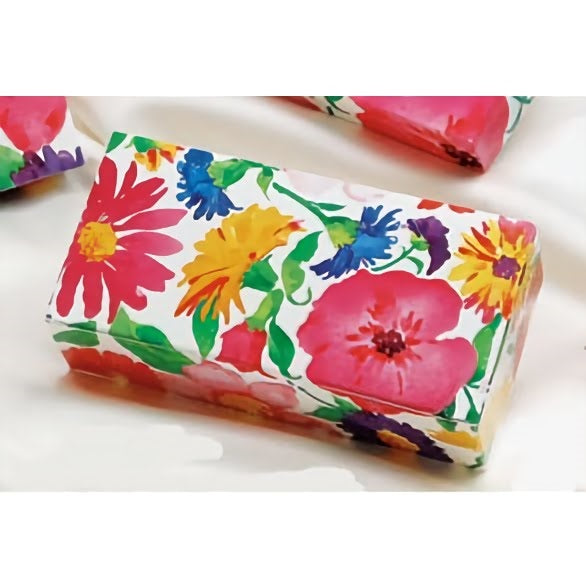 The image displays a one-pound candy box with a vibrant and colorful spring flower design. The pattern is bold and lively, featuring large floral prints in red, yellow, pink, blue, and purple, with green foliage accents. 