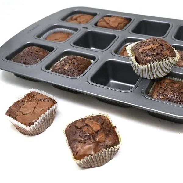 Square baking pan filled with chocolate brownies, some removed and placed beside the pan.