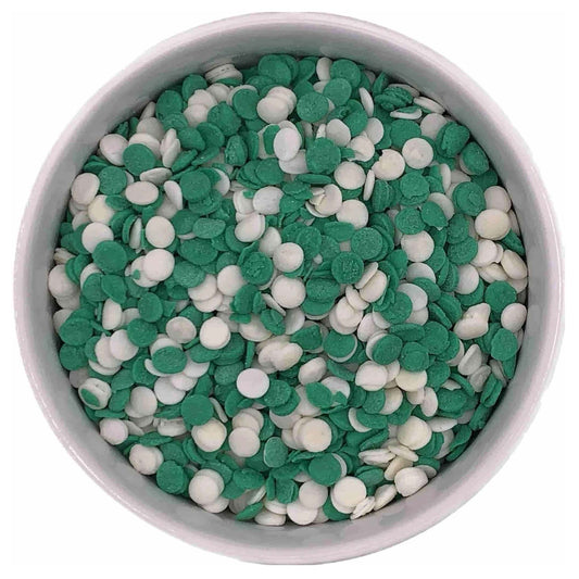 White bowl filled with green and white round sprinkles, commonly used as edible decorations for cakes, cookies, and desserts.