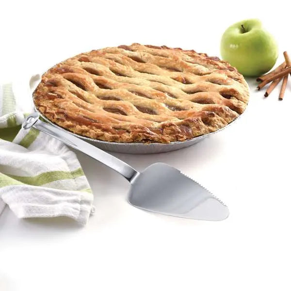 Stainless steel mini pie server next to a golden lattice apple pie with a fresh apple and cinnamon sticks in the background.