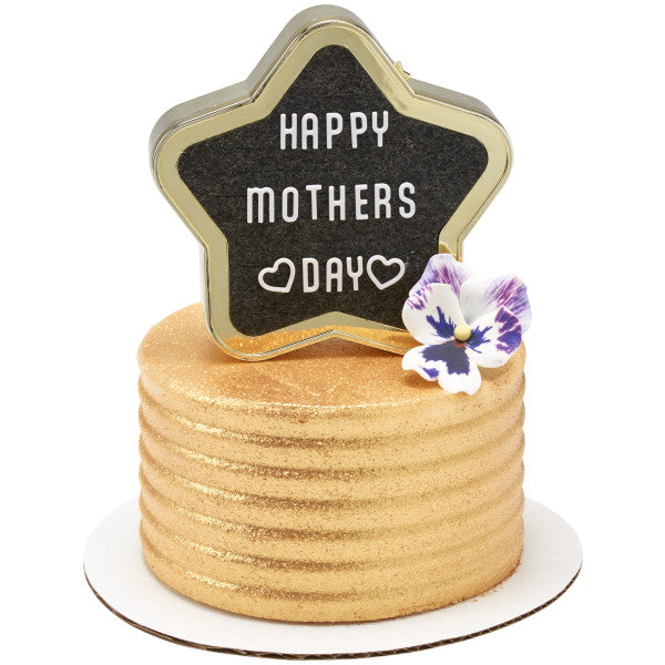 A gold-textured cake decorated with an edible flower, featuring the Star Grad Letter Board DecoSet with "HAPPY MOTHERS DAY" written in white letters.