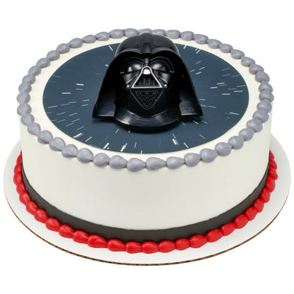 Round cake with a Star Wars space background, decorated with a Darth Vader topper and red and silver icing accents.