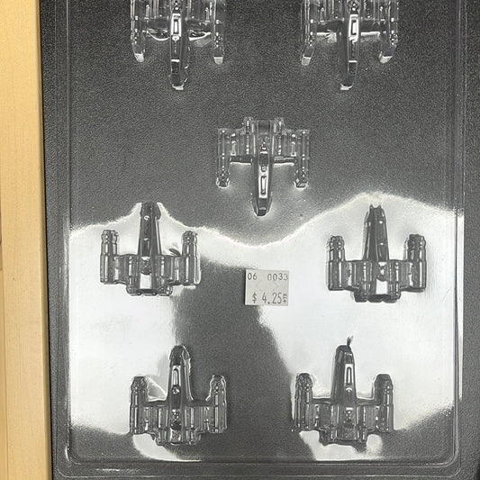 Clear plastic chocolate mold with six cavities designed to create chocolates shaped like the X-wing starfighters from Star Wars, featuring detailed wings and cockpit sections.