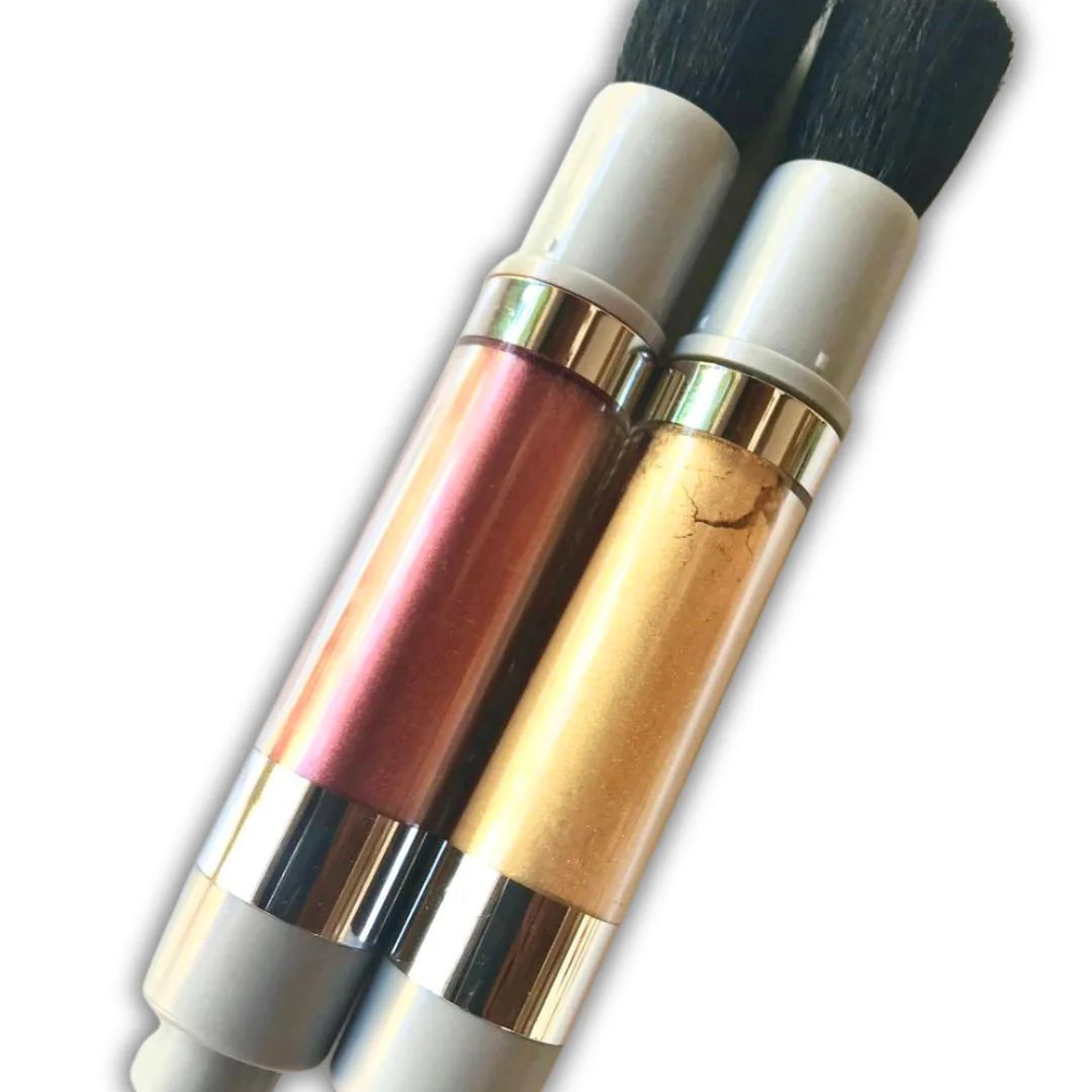 Close-up of two pump brushes filled with edible dust—one in metallic red and one in gold—used for decorating cakes, cookies, and sugar art with shimmer.