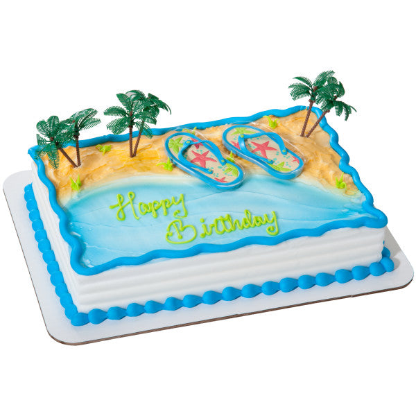 A rectangular cake decorated with the Life’s a Beach DecoSet®, featuring flip-flops and palm trees on a sandy beach and ocean-themed design.