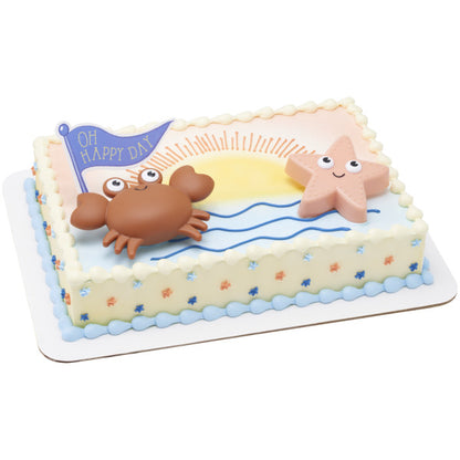 A rectangular cake decorated with ocean waves, a sunrise, and Beach Buddies toppers.