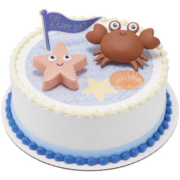 A round cake featuring a water-themed design, topped with the crab, starfish, and flag.