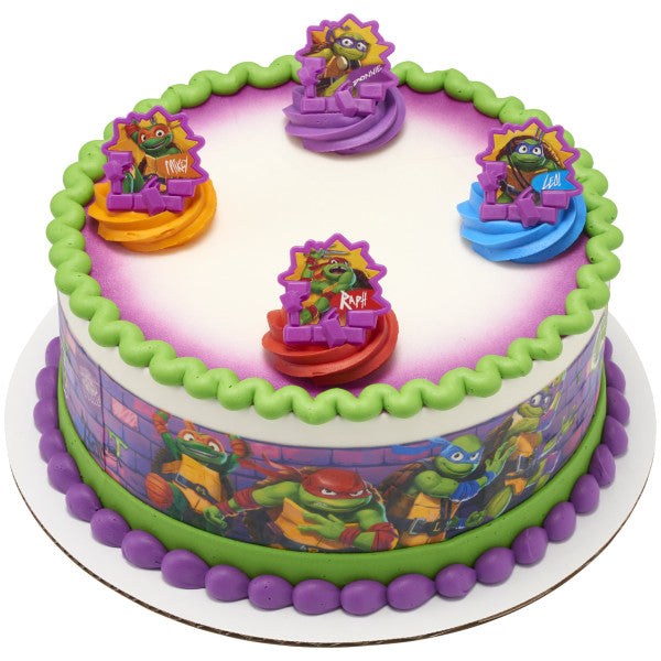 Round birthday cake decorated with Teenage Mutant Ninja Turtles rings and character wrap, with colorful frosting and piping