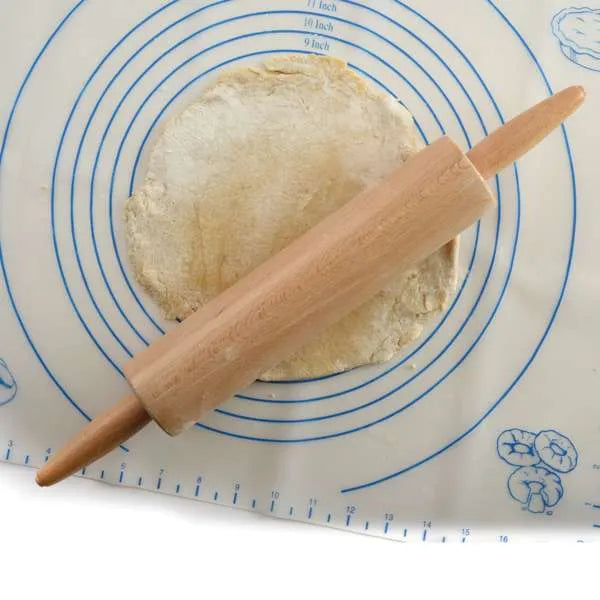 Traditional wooden rolling pin rolling out dough on a silicone baking mat with concentric circles and measurements.