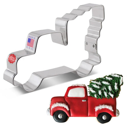 Truck hauling a Christmas tree cookie cutter alongside a decorated cookie featuring a red truck with a green tree in the back.