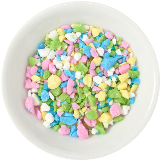 Close-up of tutti frutti sugar candy decorations in a white bowl, featuring colorful crushed candy in pink, yellow, green, blue, and white.