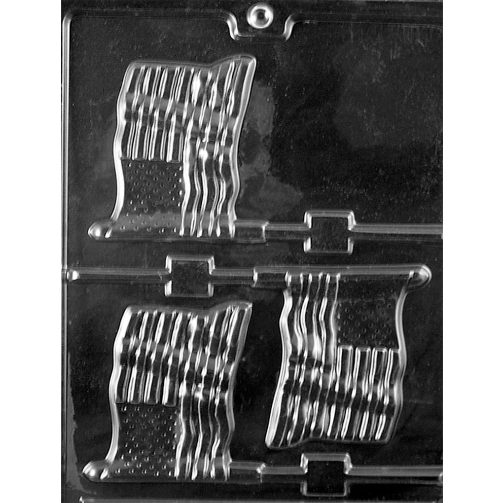 Clear plastic chocolate lollipop mold photographed on a dark background with three waving U.S. flag cavities, showing raised stripes, a dotted star field, and stick channels.