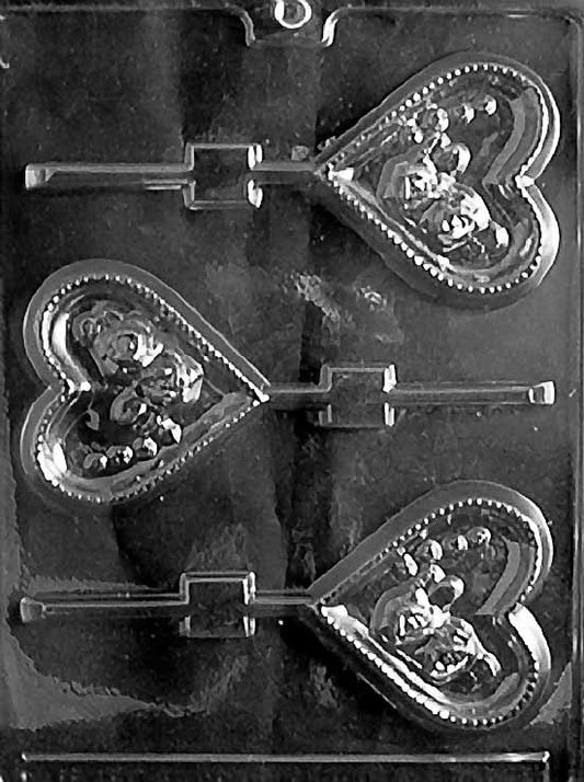 HEART WITH ROSES Lollipop chocolate mold with heart-shaped lollipop cavities decorated with roses; clear sheet.