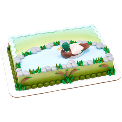 A rectangular cake decorated to look like a pond with a duck floating in the center.