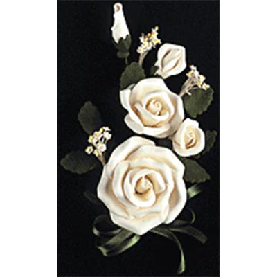 Gum paste white tea rose spray with multiple roses, buds, green leaves, and filler flowers arranged on a black background