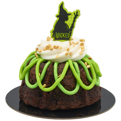 Mini chocolate bundt cake with green drizzle and white frosting swirl, finished with a green Wicked pick featuring Elphaba’s silhouette.